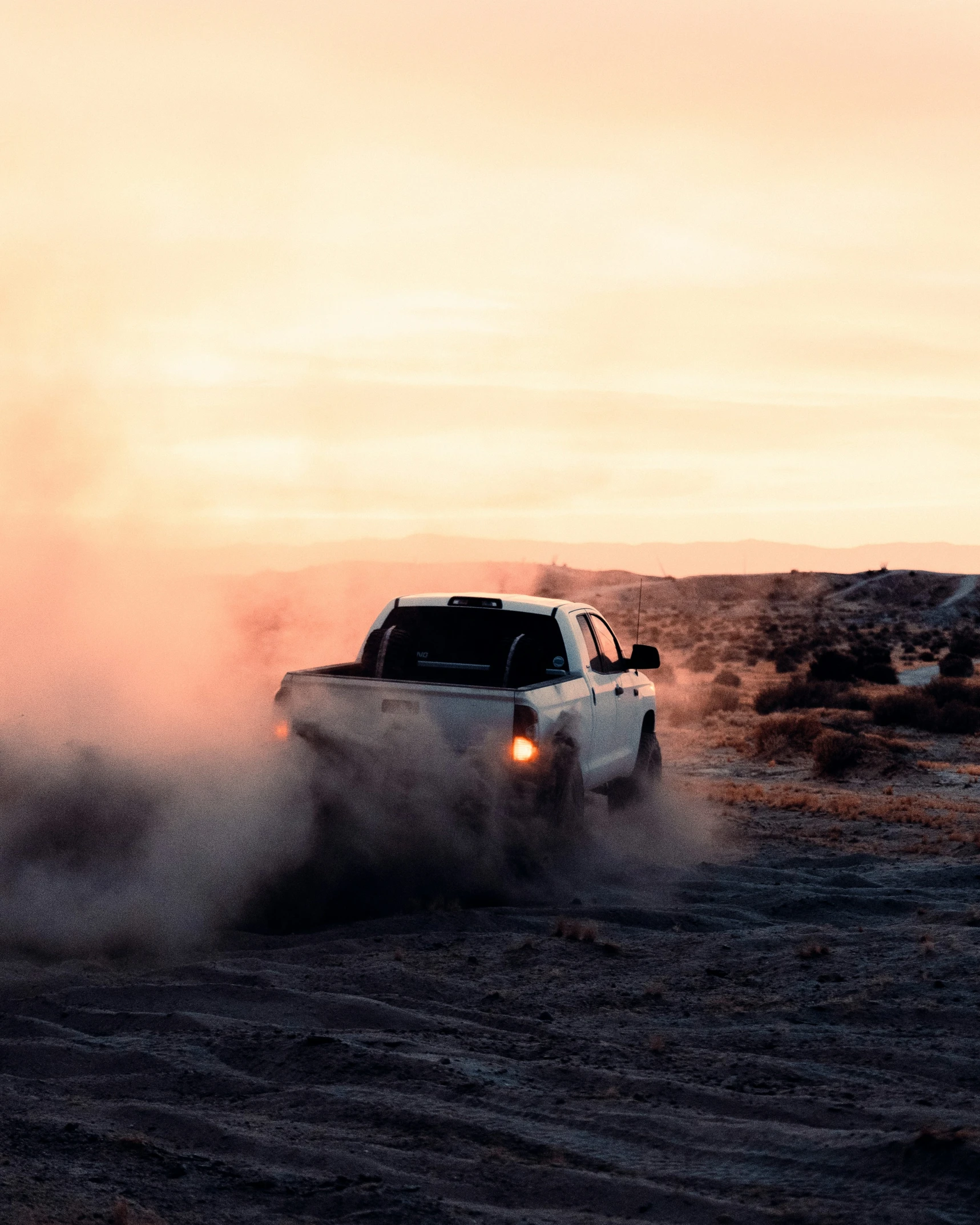 the truck is driving through the dust in the desert