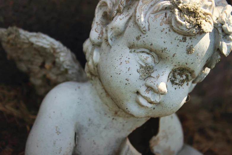an angel statue sits outside on dirt