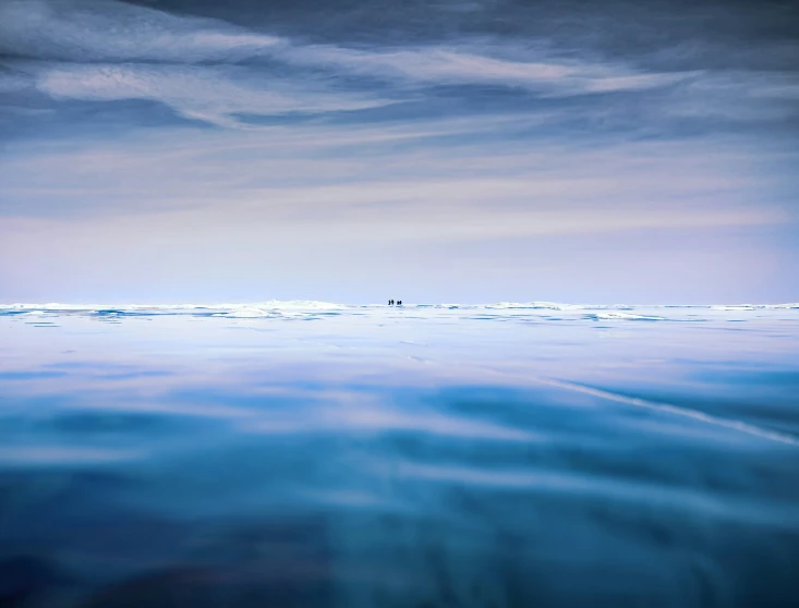 two people are standing in the ocean on a cloudy day