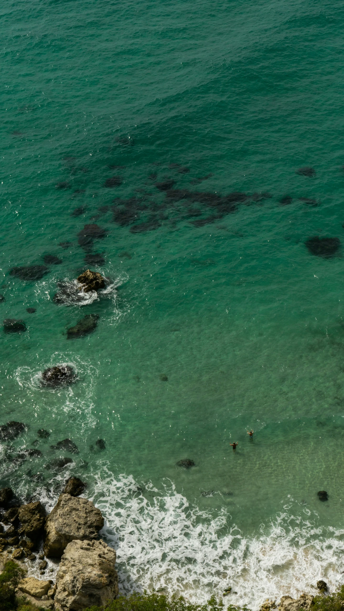 an aerial view of the ocean, with many rocks and water