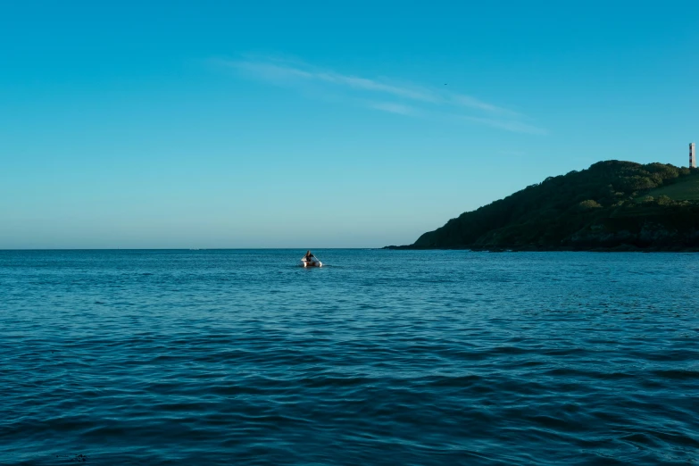 a small boat in the ocean near a hill