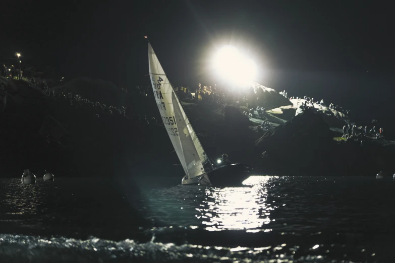 a sail boat with white sail, floating on the water