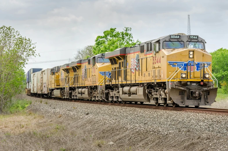 train pulling multiple cars passing through a rural area