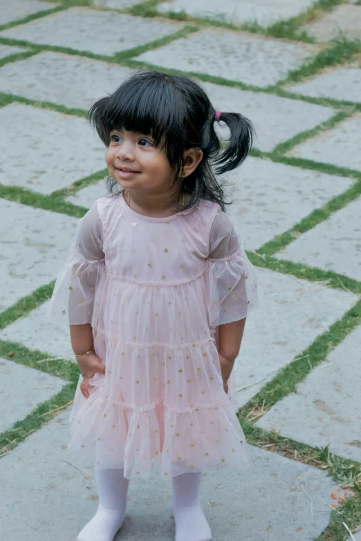 a girl in pink dress standing near some stone floors