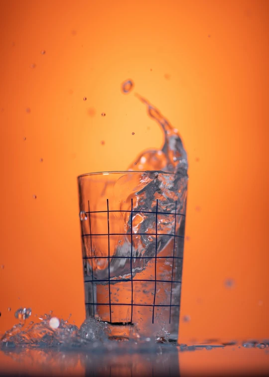 a half full glass and an orange background