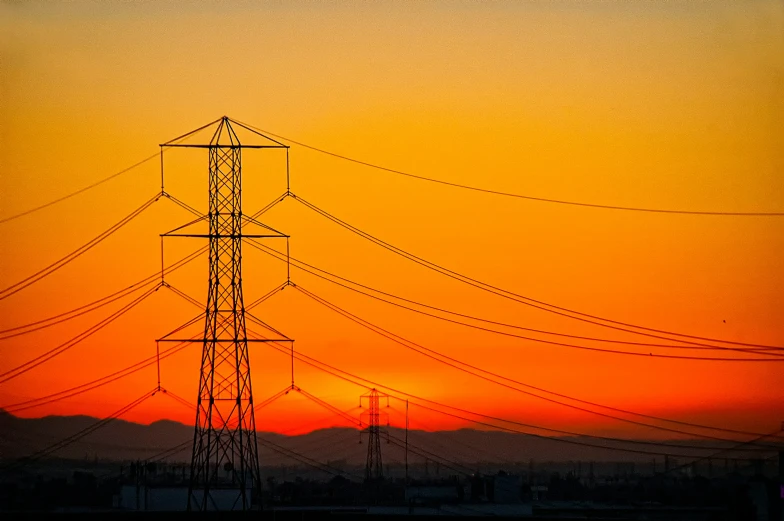 the sun sets behind some high voltage wires