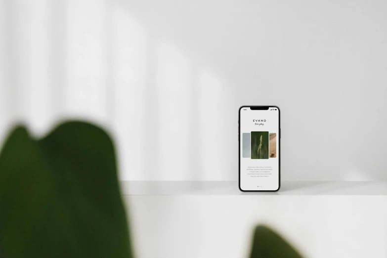 a cell phone sitting on top of a table next to a green plant