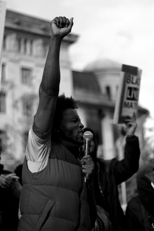 a man raising his fist during a protest outside a large building