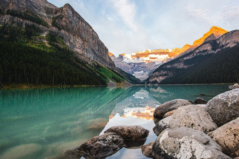 the rocky shore of a mountain lake in front of snowy mountains