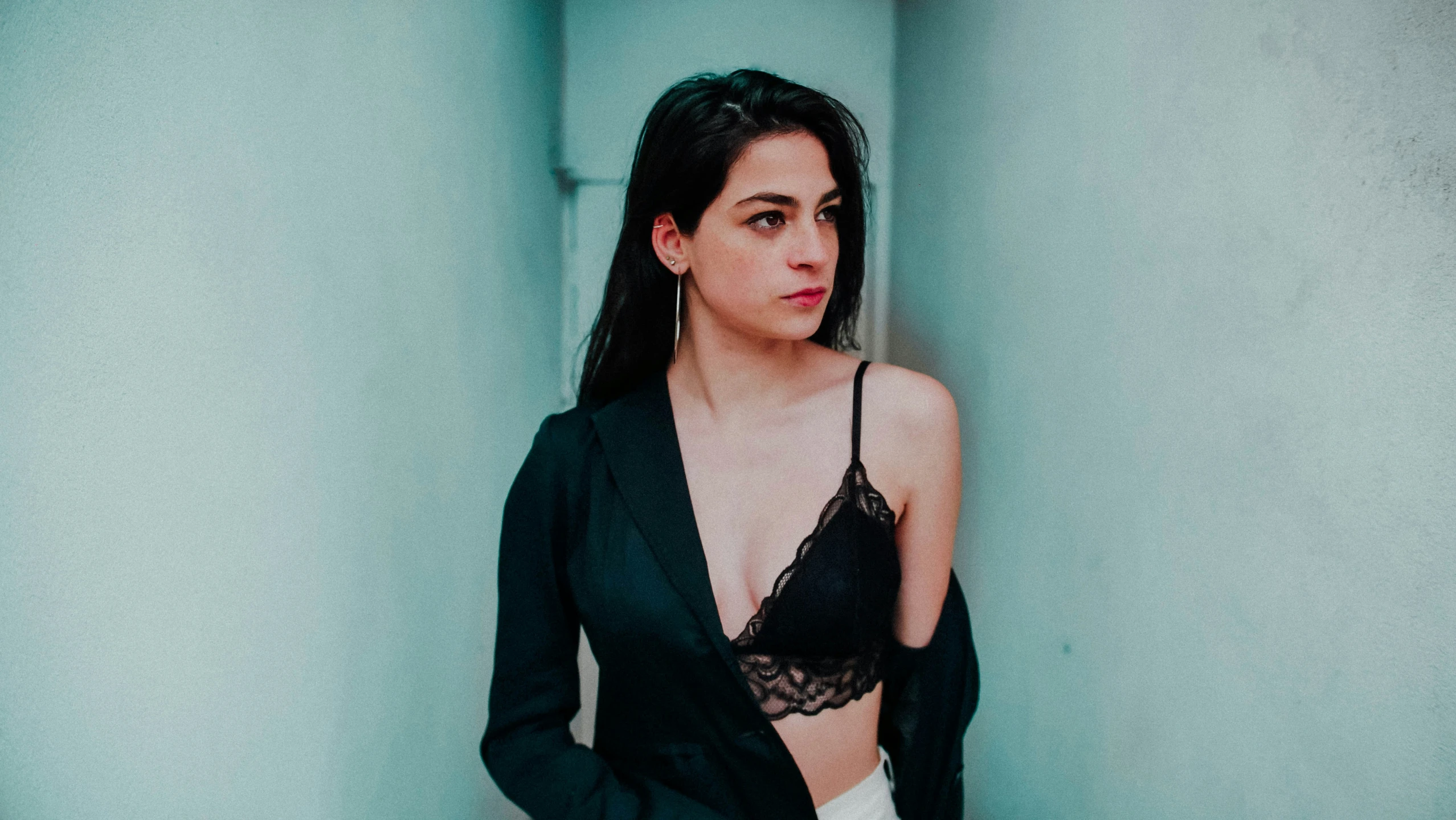 a girl in black blouse and white panties standing next to green wall