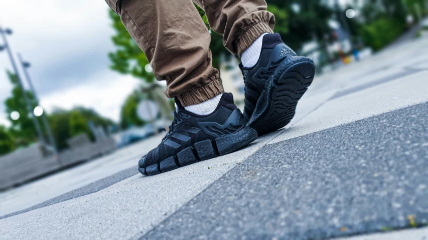 a person with brown pants and socks walks down a sidewalk