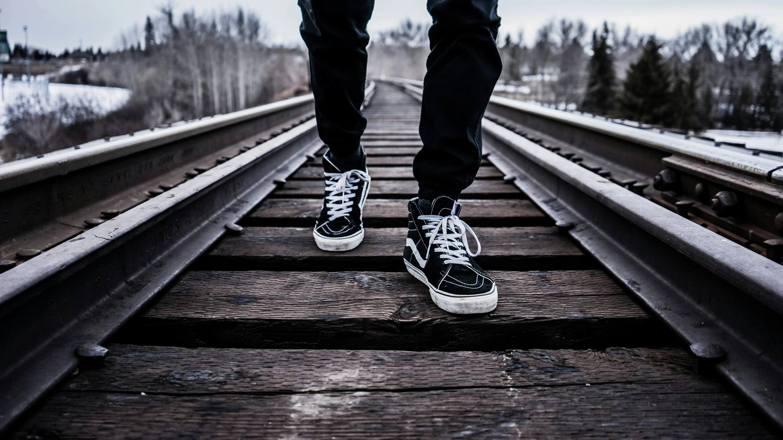 someone is walking down a train track with black shoes