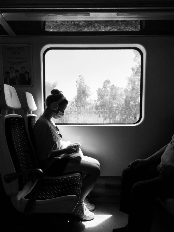 a woman sitting in a seat on the side of a train