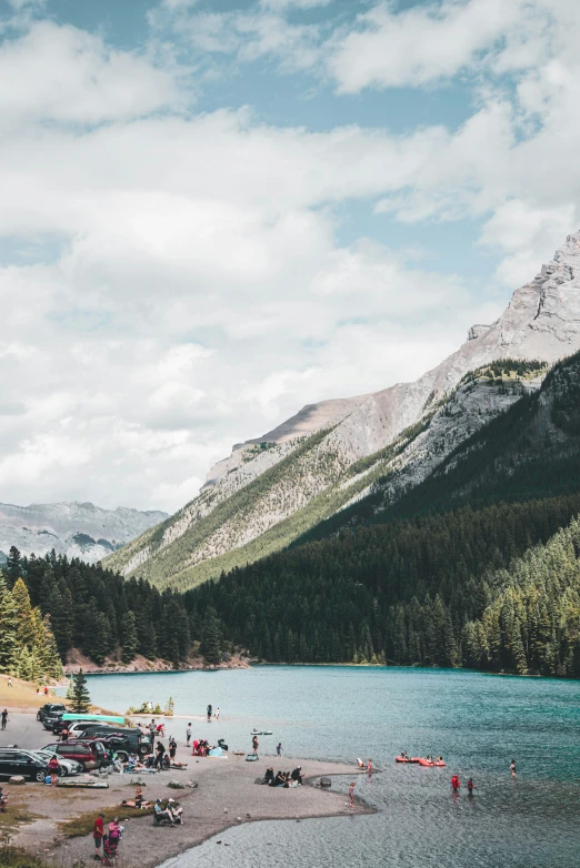 a lake surrounded by mountains is filled with people and vehicles