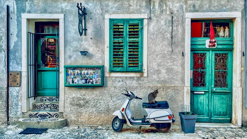 a scooter parked next to the wall near some green doors