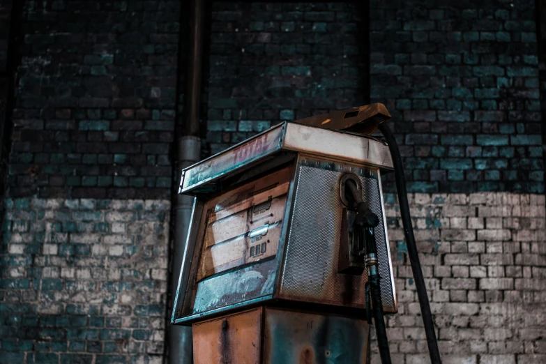 an old rusty and broken machine in front of a brick wall