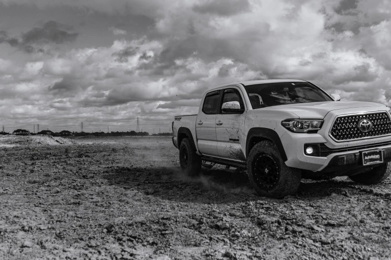 a white truck parked in the desert on a cloudy day