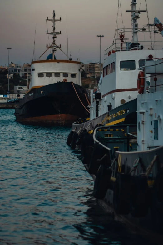 two large ships docked in a bay at dusk