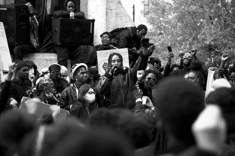 an urban crowd holds up placards in protest with a black man at one end