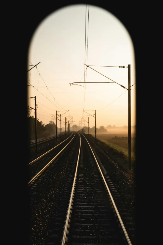 train tracks stretching to a sunset with a view of power lines