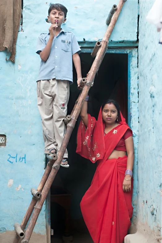 two children in front of a building, one on a ladder and the other on a boat