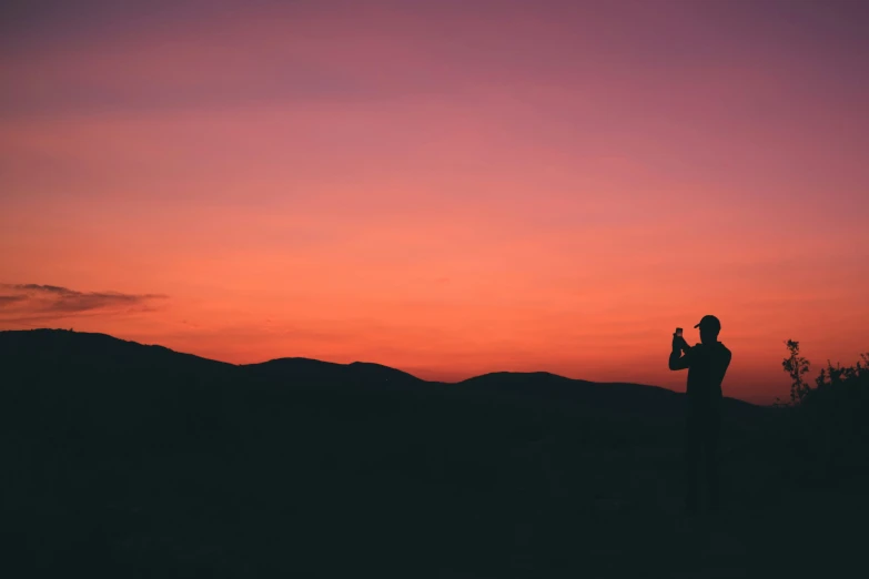 a man standing in front of an orange and pink sky