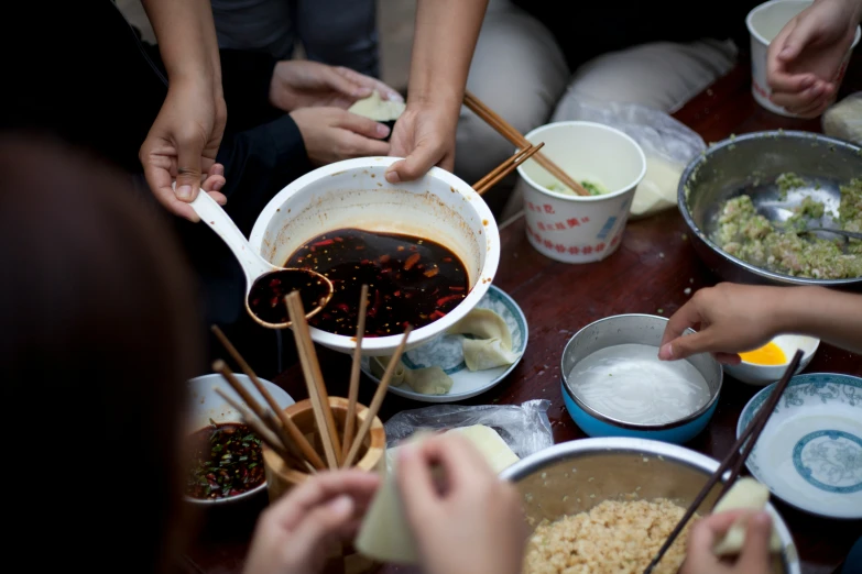 several people are preparing food around the table