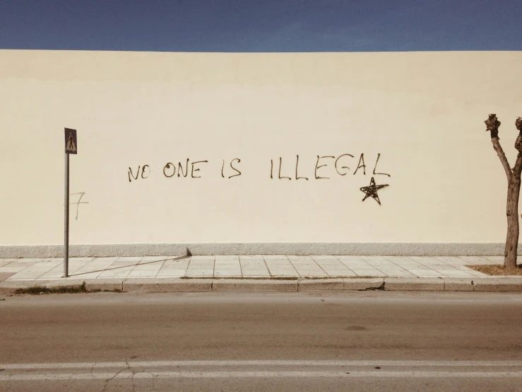 graffiti on the side of a white wall that says welcome illegal
