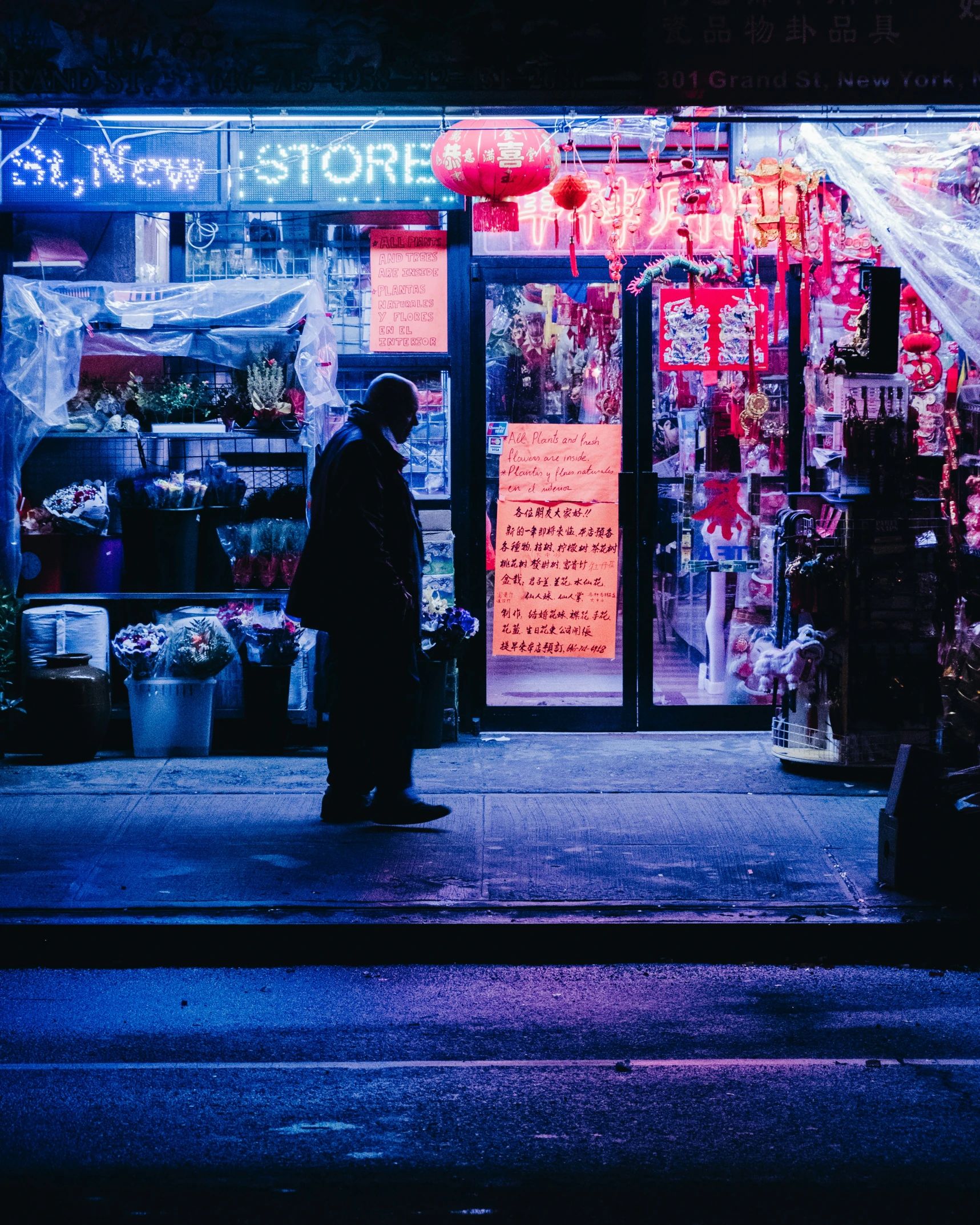 the woman is waiting outside of a store at night