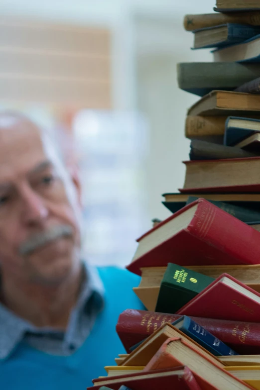 a man holding a stack of books, one with a book open and another is looking down