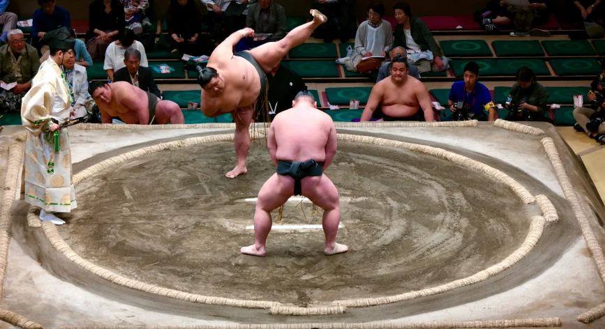 sumo wrestlers perform an aerial stunt during the day