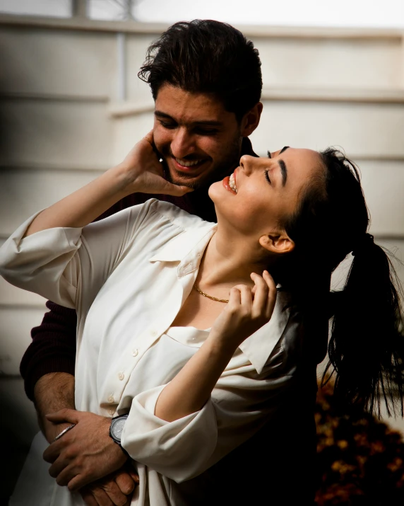 the man is smiling and hugging the woman in front of her