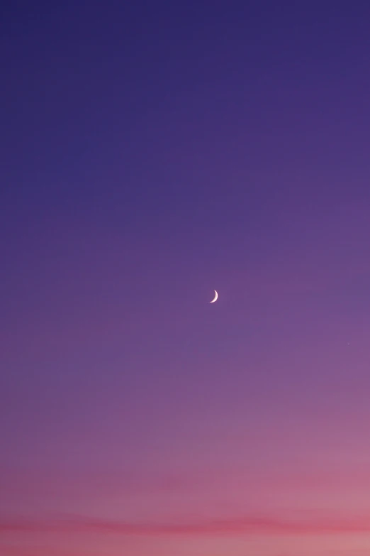 a distant crescent moon in the dark sky