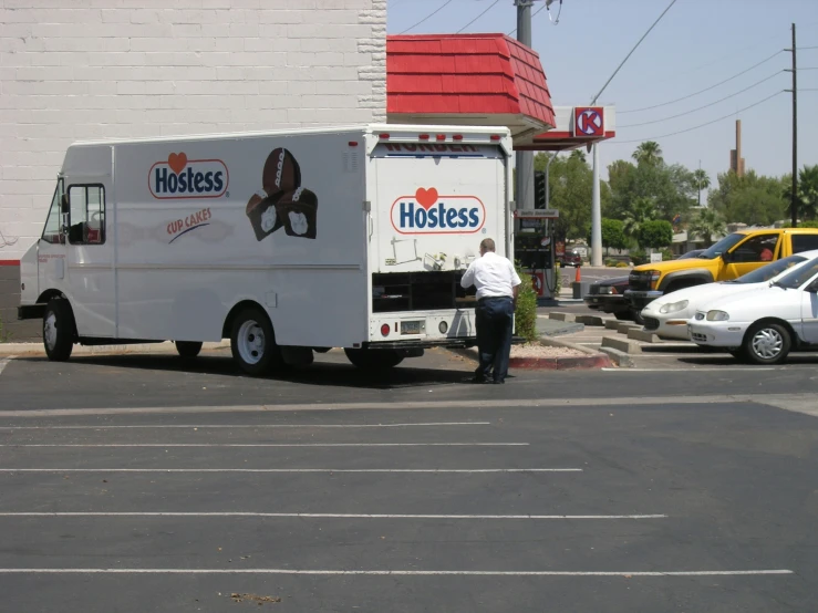 there is a man standing in front of a food truck that is parked on the side of the road