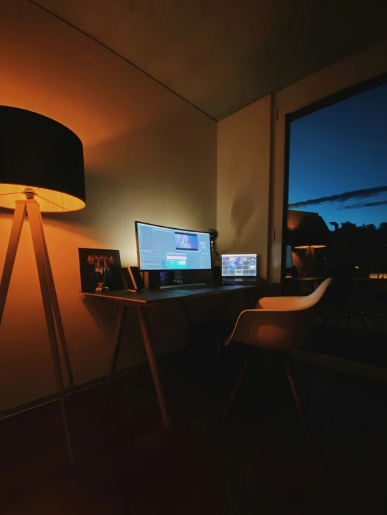 a lamp a table a computer monitor a keyboard and some lights
