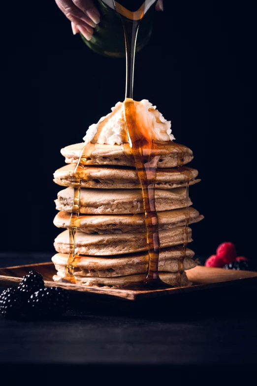 a stack of pancakes with syrup being poured over top