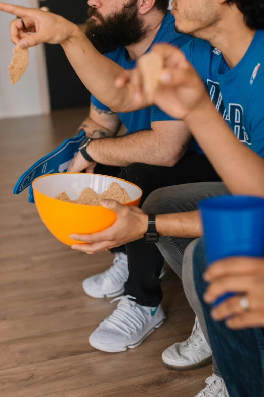 a man and a woman sit on a couch while eating from a bowl