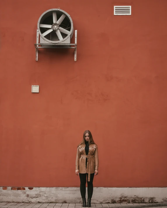 a woman standing in front of an orange wall