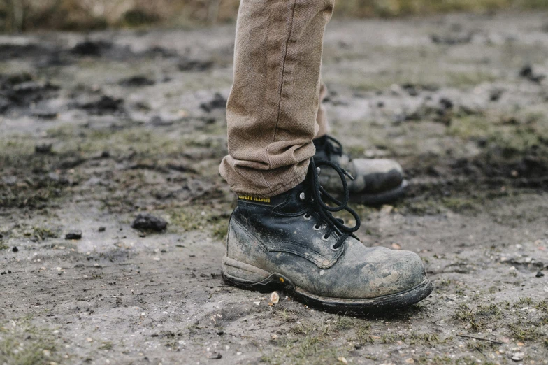 a pair of shoes with no laces standing on a dirty field