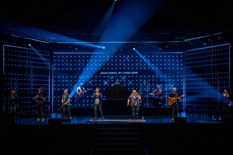 the group are standing in front of a microphone on a stage