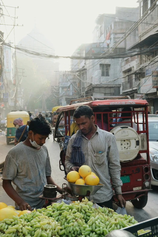 people selling produce at an outdoor market in a busy street