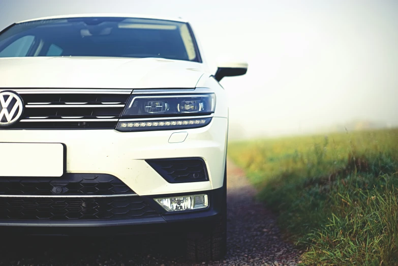 the front end of a white car on a dirt road