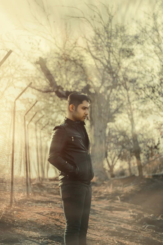 a man in leather stands in front of trees