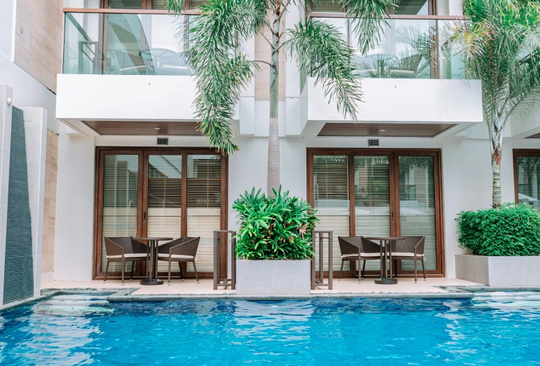 a swimming pool with lounge chairs outside the entrance of an apartment