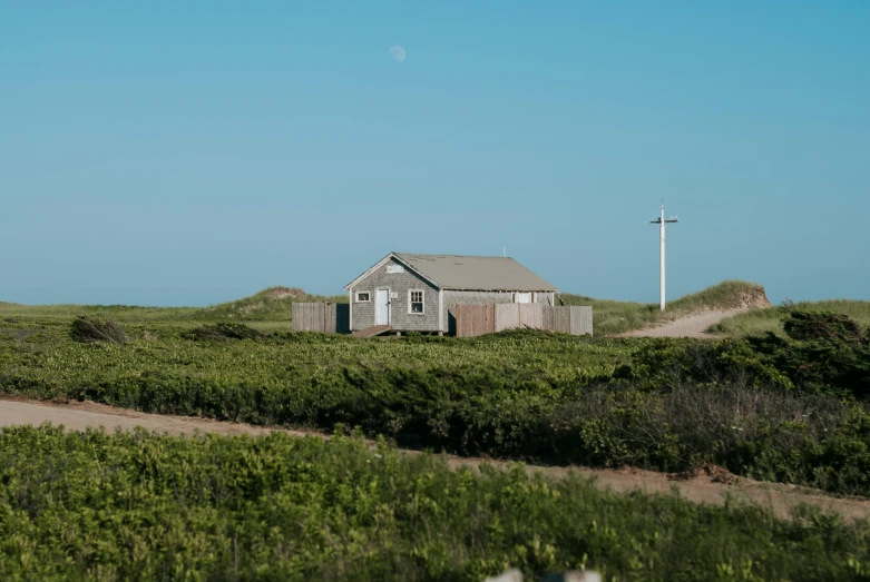 an outhouse sits on the side of a small, grassy hill