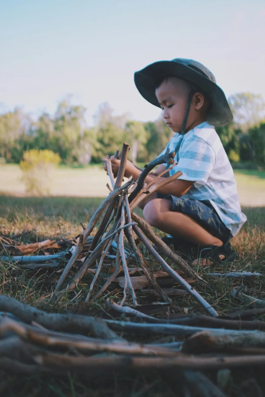 a boy sitting on the ground near a pile of nches