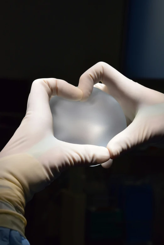 two hands hold the silver ball with a heart shaped shape