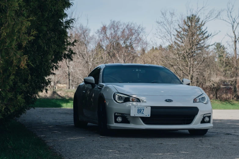 the front end of a silver sports car parked on gravel