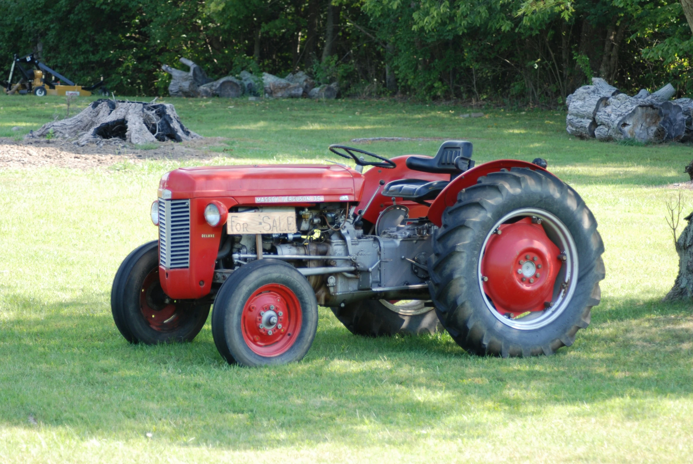 a red tractor is parked in the grass