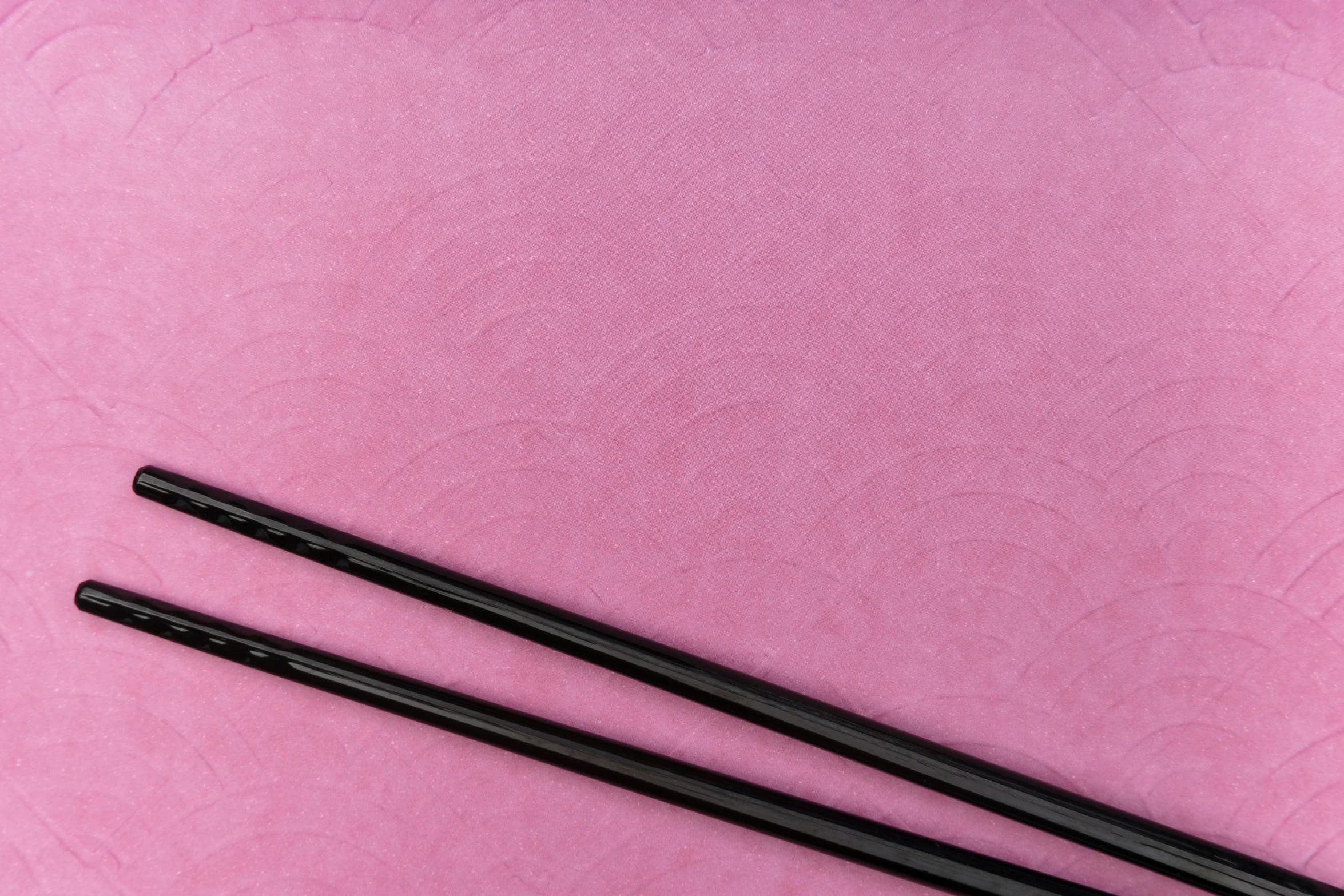 three chopsticks in front of pink background